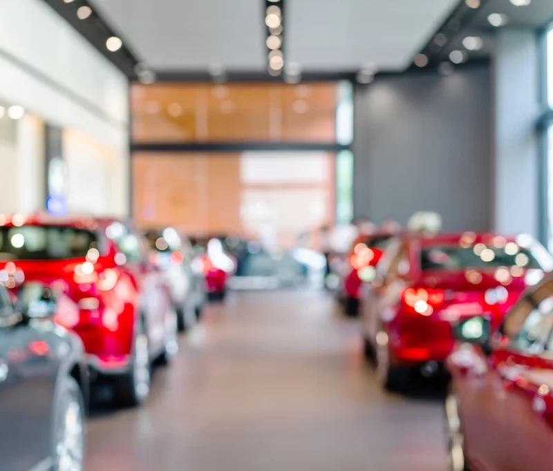 Two rows of red cars parked inside a car dealership.